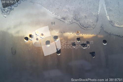 Image of Water drops, ice pattern and sunlight on window glass