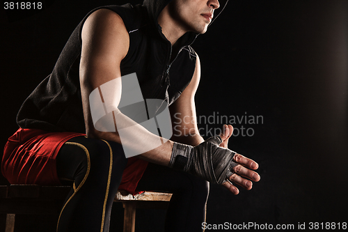 Image of The muscular man sitting and resting on black