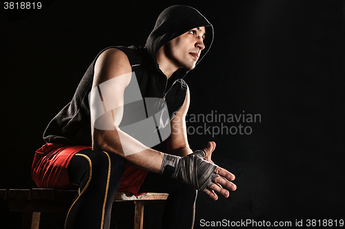 Image of The muscular man sitting and resting on black