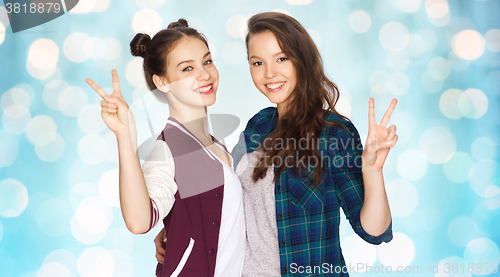 Image of happy teenage girls hugging and showing peace sign