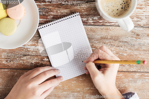 Image of close up of hands, notebook, coffee and cookies