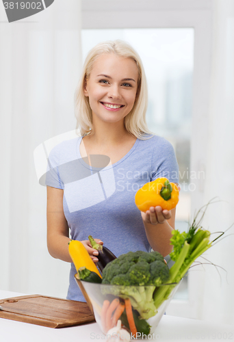 Image of smiling young woman cooking vegetables at home