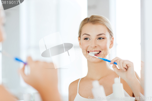 Image of woman with toothbrush cleaning teeth at bathroom