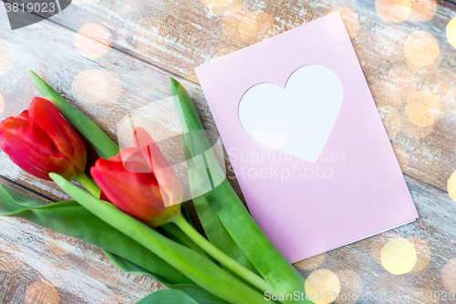 Image of close up of tulips and greeting card with heart