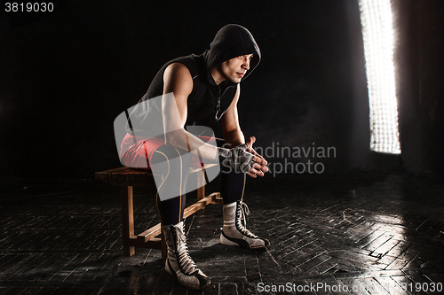 Image of The muscular man sitting and resting on black