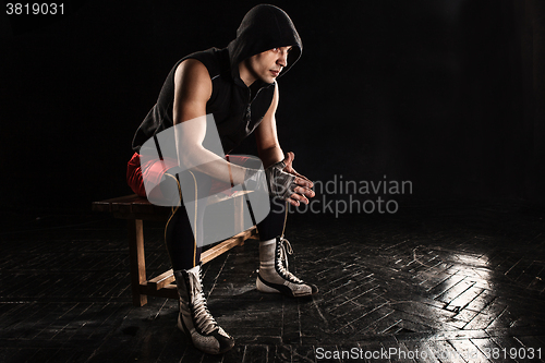 Image of The muscular man sitting and resting on black