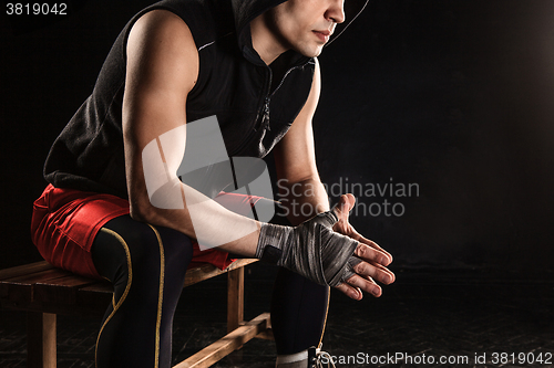 Image of The muscular man sitting and resting on black
