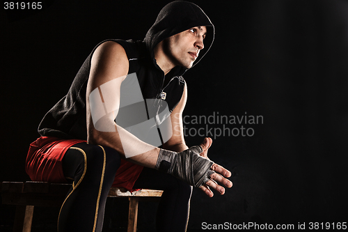 Image of The muscular man sitting and resting on black