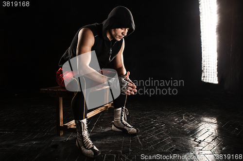 Image of The muscular man sitting and resting on black