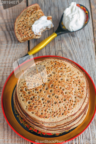 Image of Whole grain pancakes and a spoon of sour cream.