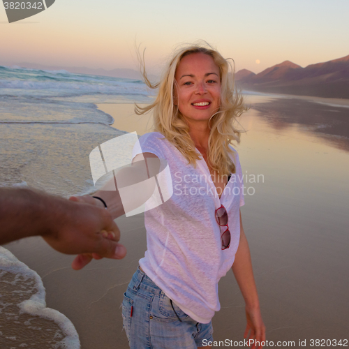 Image of Romantic couple, holding hands, having fun on beach.