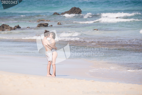 Image of Young couple kissing on sandy beach.