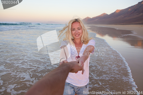 Image of Romantic couple, holding hands, having fun on beach.