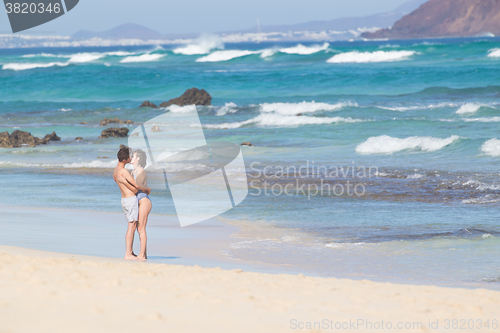 Image of Young couple kissing on sandy beach.