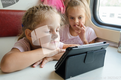 Image of Two girls on a train with interest looking cartoon Tablet PC