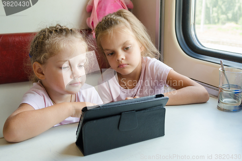 Image of Two girls on a train watching a cartoon in the plate