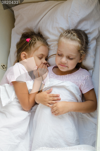 Image of  Two girls pretending that sleep on the bottom shelf in a train
