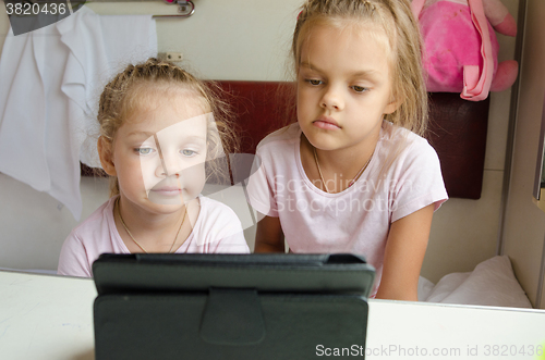 Image of Sisters looking at tablet in the train