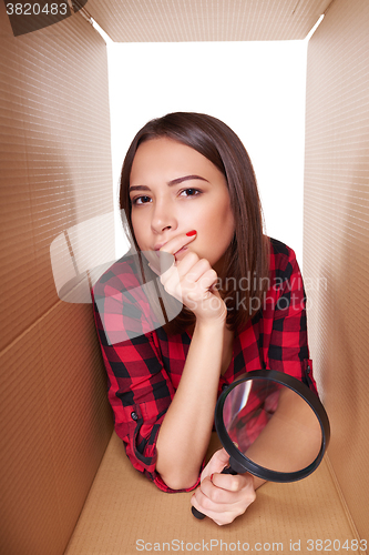 Image of Female peeking into carton box looking through magnifying glass