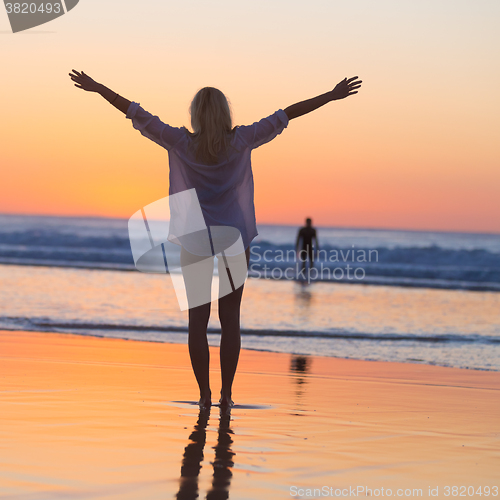 Image of Free woman enjoying vacations on beach at sunset.