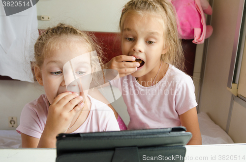 Image of Sisters eating and looking at the tablet in the train