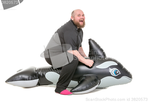 Image of Fat Man Fun Jumping on an Inflatable Dolphin