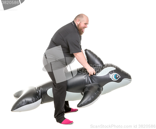 Image of Fat Man Fun Jumping on an Inflatable Dolphin