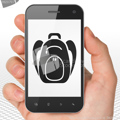 Image of Vacation concept: Hand Holding Smartphone with Backpack on display