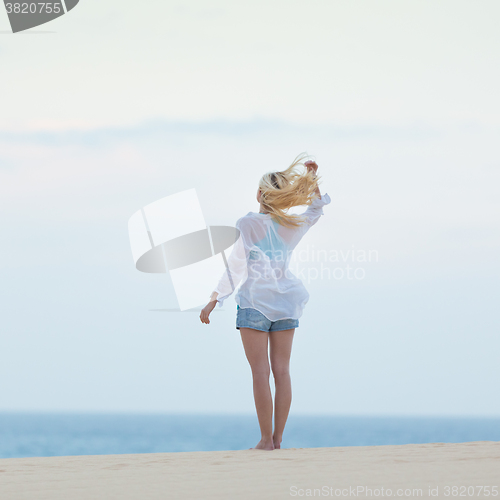 Image of Woman on sandy beach in morning. 
