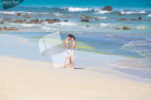 Image of Young couple kissing on sandy beach.