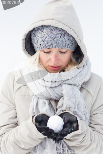 Image of Girl  holding snowball in cold winter time.
