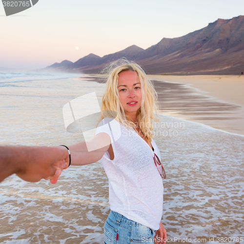 Image of Romantic couple, holding hands, having fun on beach.