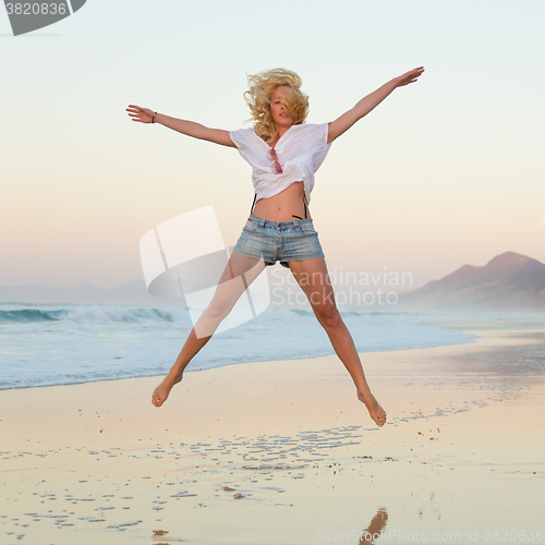 Image of Young beautiful woman jumping in the beach.