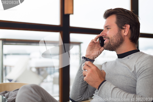 Image of Informal businessman talking on phone by window.