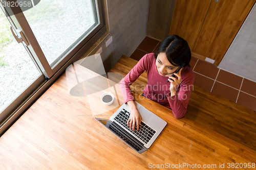 Image of Top view of woman talk to cellphone and use of the notebook comp