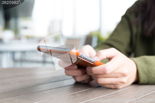 Image of Woman texting on her mobile phone at outdoor cafe