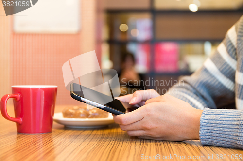 Image of Woman texting message on cellphone at cafe