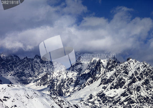 Image of High snowy mountains in clouds at sunny day