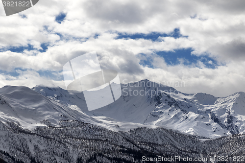 Image of View on snowy mountains and cloudy sky in evening