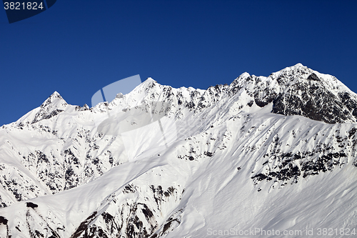 Image of Snowy mountains and blue clear sky at sun day