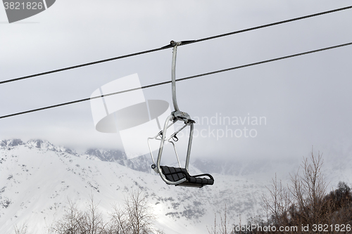 Image of Chair lift and snowy mountains in haze