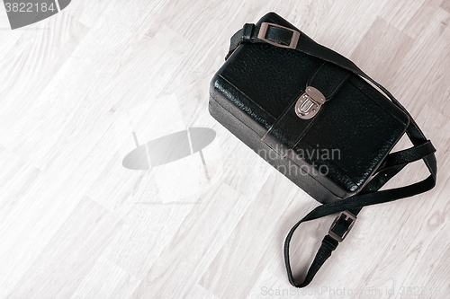 Image of Vintage black leather case on a wooden floor