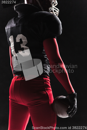 Image of American football player posing with ball on black background