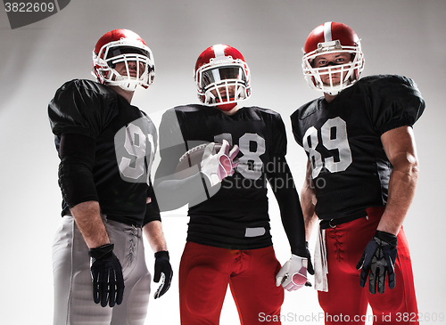 Image of The three american football players posing with ball on white background