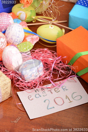 Image of Easter with eggs in nest and yellow tulips over blue wooden table. Top view