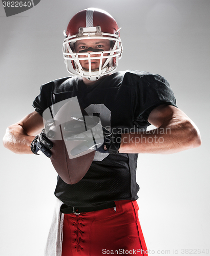 Image of American football player posing with ball on white background