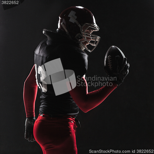 Image of American football player posing with ball on black background