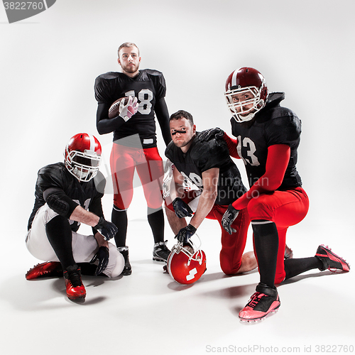 Image of The four american football players posing with ball on white background