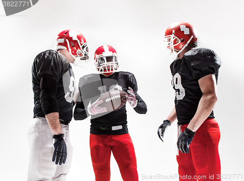 Image of The three american football players posing with ball on white background