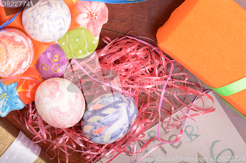 Image of Easter with eggs in nest and yellow tulips over blue wooden table. Top view
